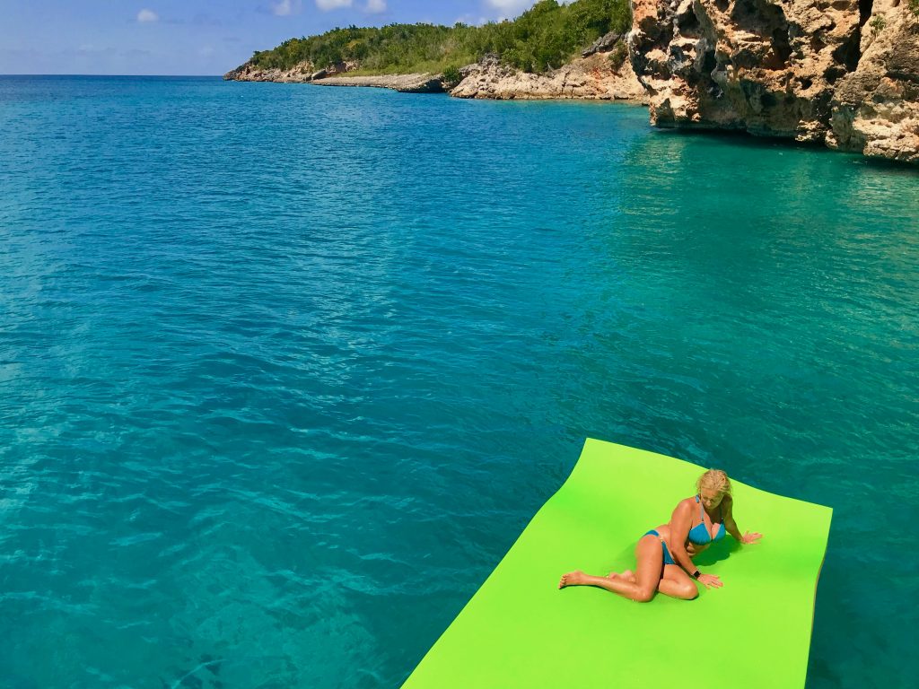 One of the guest lying on the floating mat, on the pristine water of Little Bay, facing the ocher cliffs. 