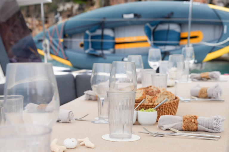 Table set up on the deck of the catamaran where a kayak can be seen in the background