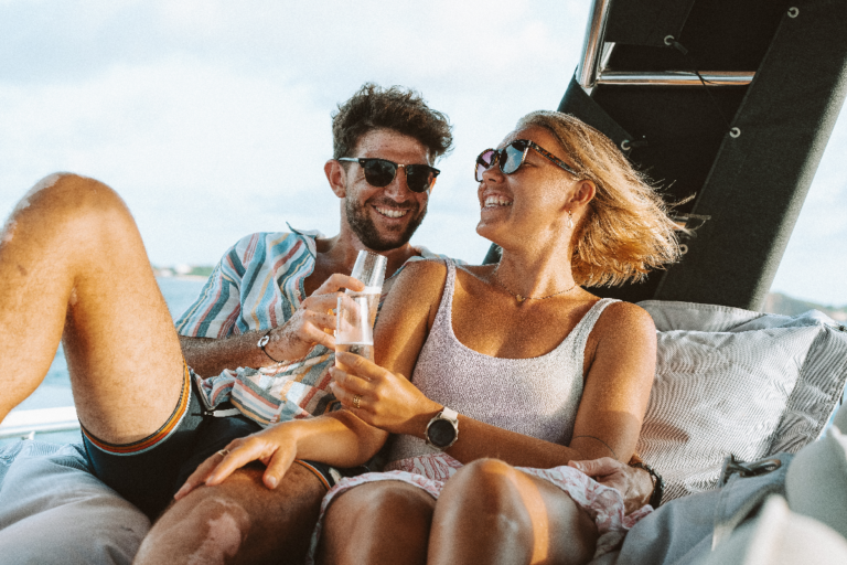 Couple toasting on the deck of our sailing catamaran during the sunset